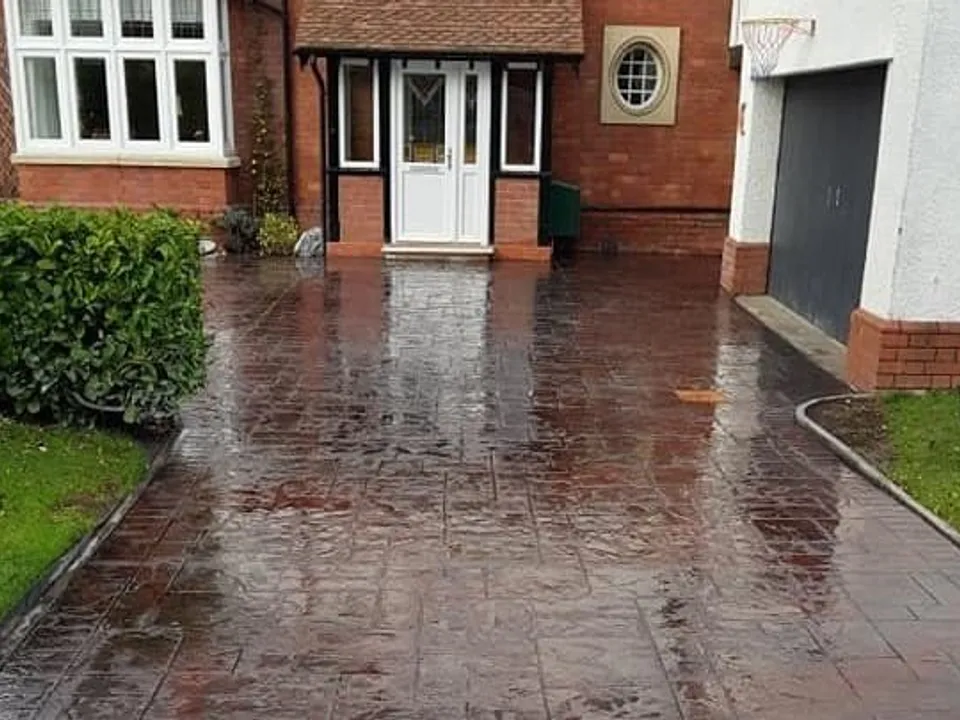 Red imprinted concrete driveway after rain